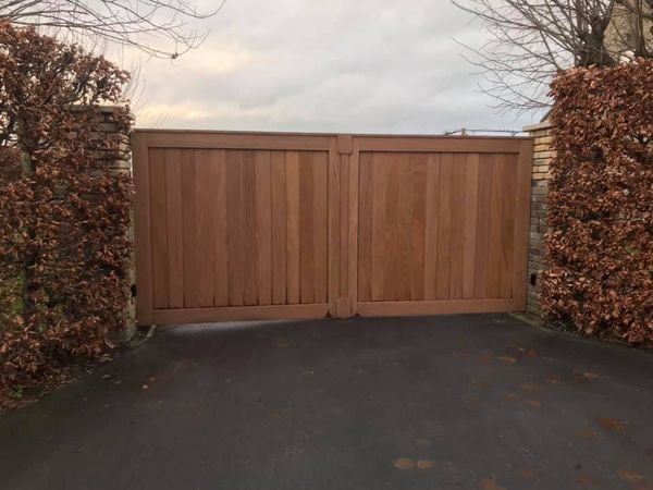 Tuinpoort in afrormosia hout tussen bakstenen zuilen in Handzame