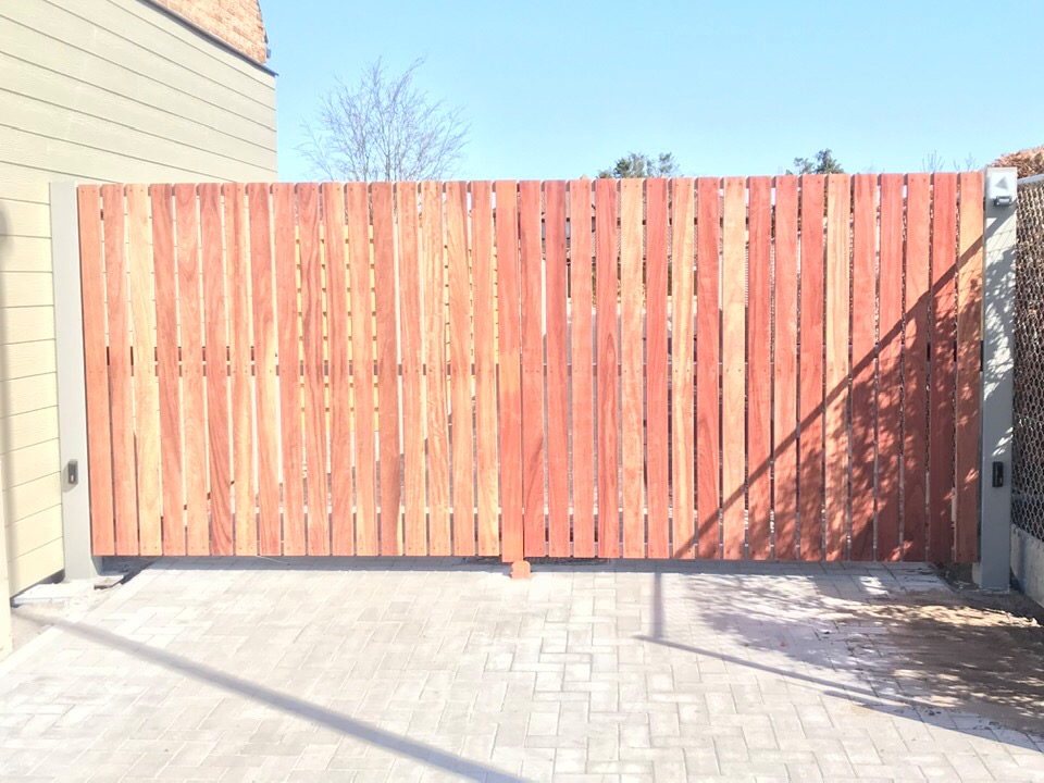 Geautomatiseerde metalen poort met padouk houten bekleding in Sint-Andries