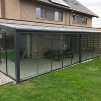 Moderne terrasoverkapping met glazen wanden aan een woning in Poelkapelle