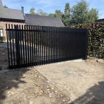 Geautomatiseerde aluminium schuifpoort met verticale spijlen, geplaatst in Roeselare-Beveren.