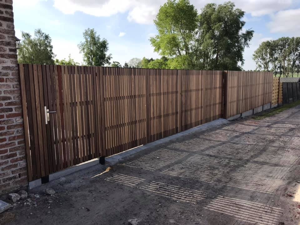 Geautomatiseerde metalen poort met padouk bekleding en doorlopende wand in Handzame