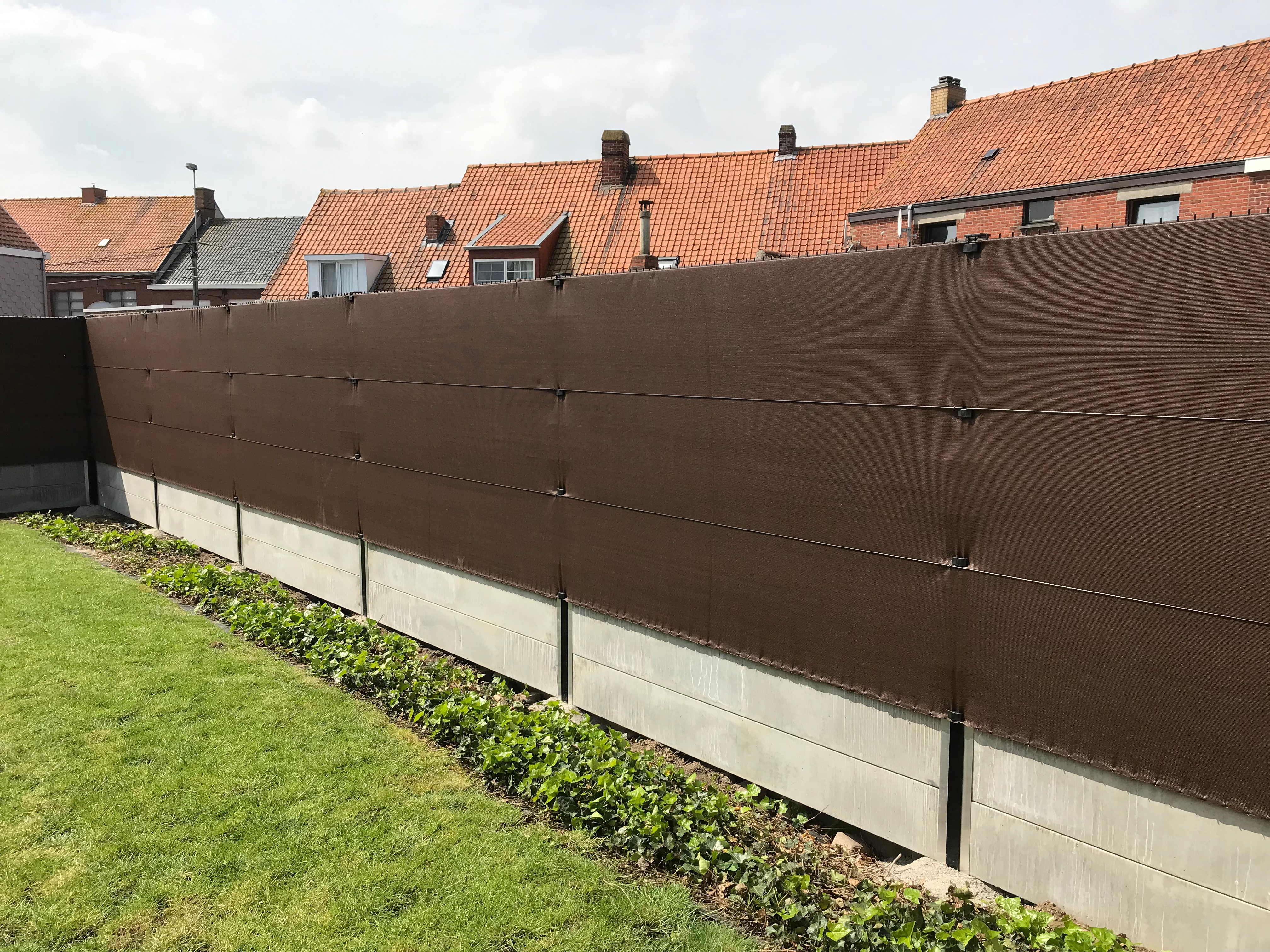 Tuinafsluiting met dubbele betonplaten en bruin zichtdoek voor extra privacy.