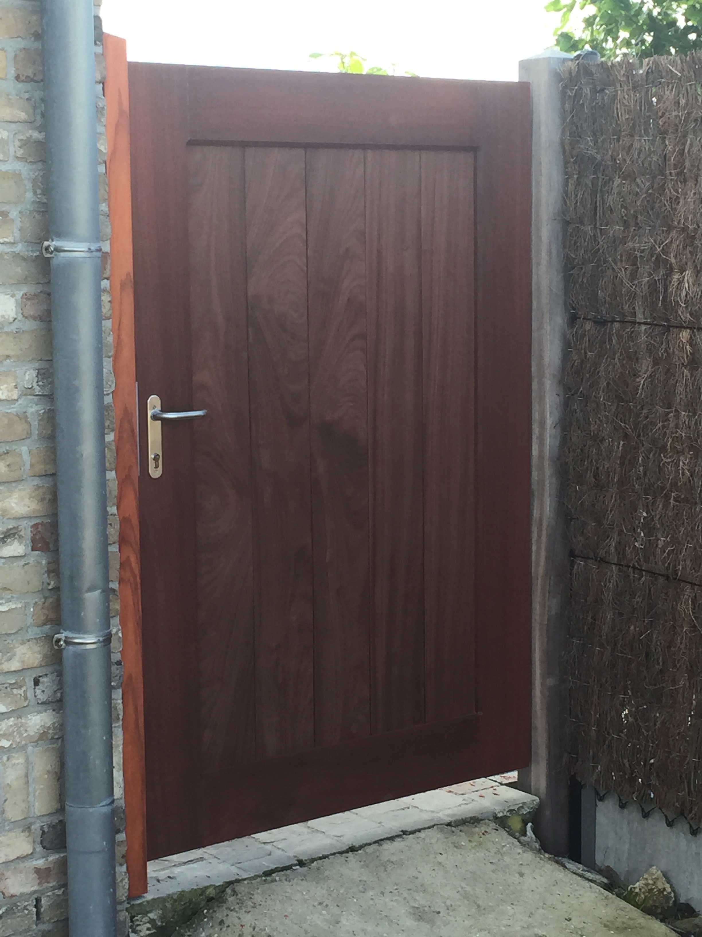 Padouk houten toegangspoortje bij een woning in Leffinge