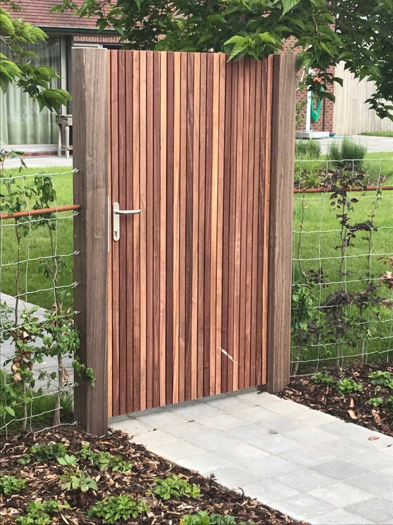 Moderne padouk tuinpoort met verticale latten in Staden