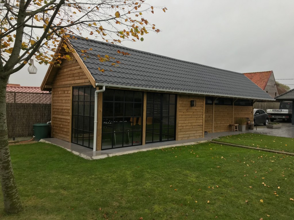 Houten bijgebouw met grote ramen en pannendak in een tuin