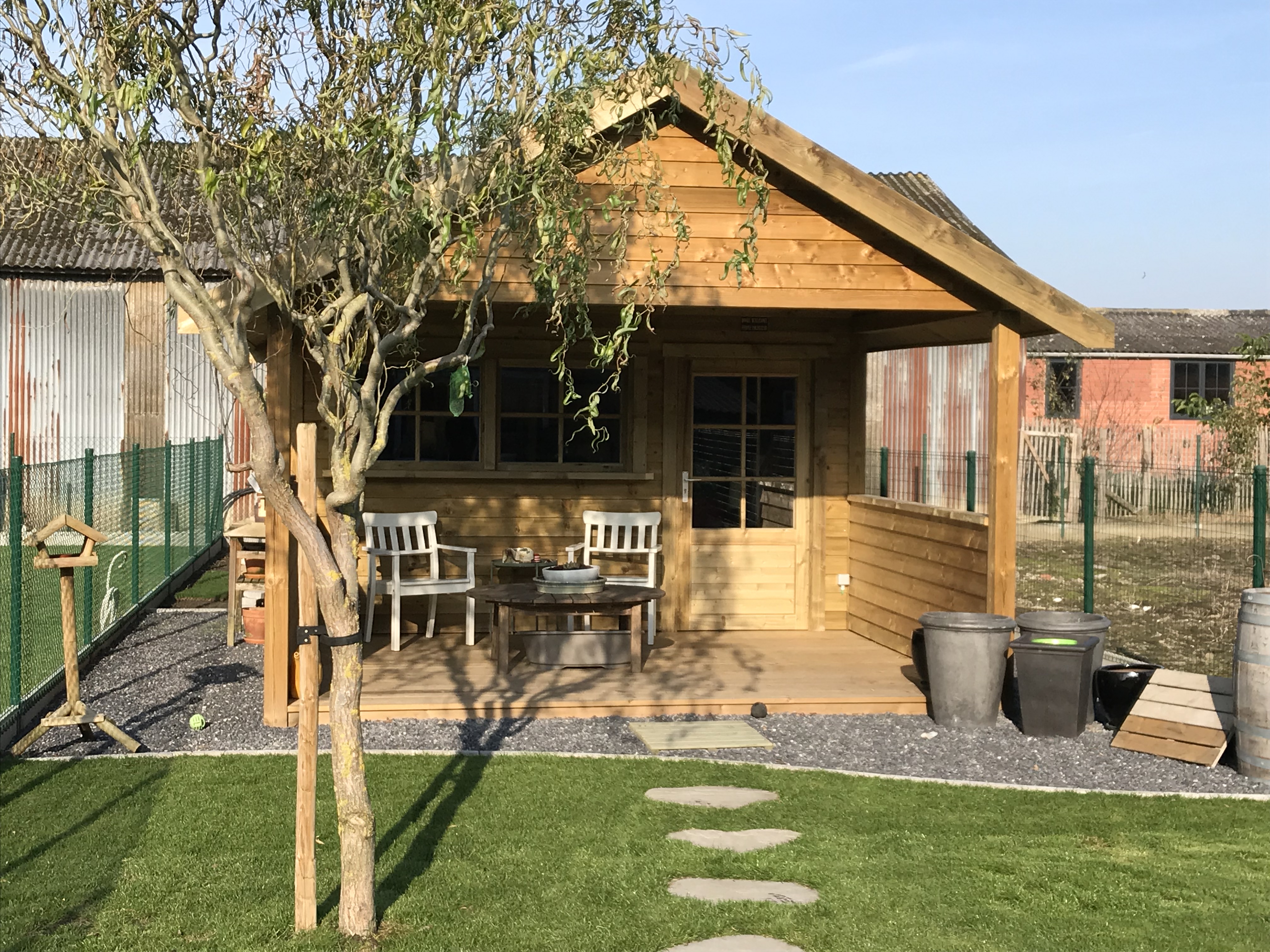 Houten tuinhuis met overdekt terras en zitplaats in de tuin