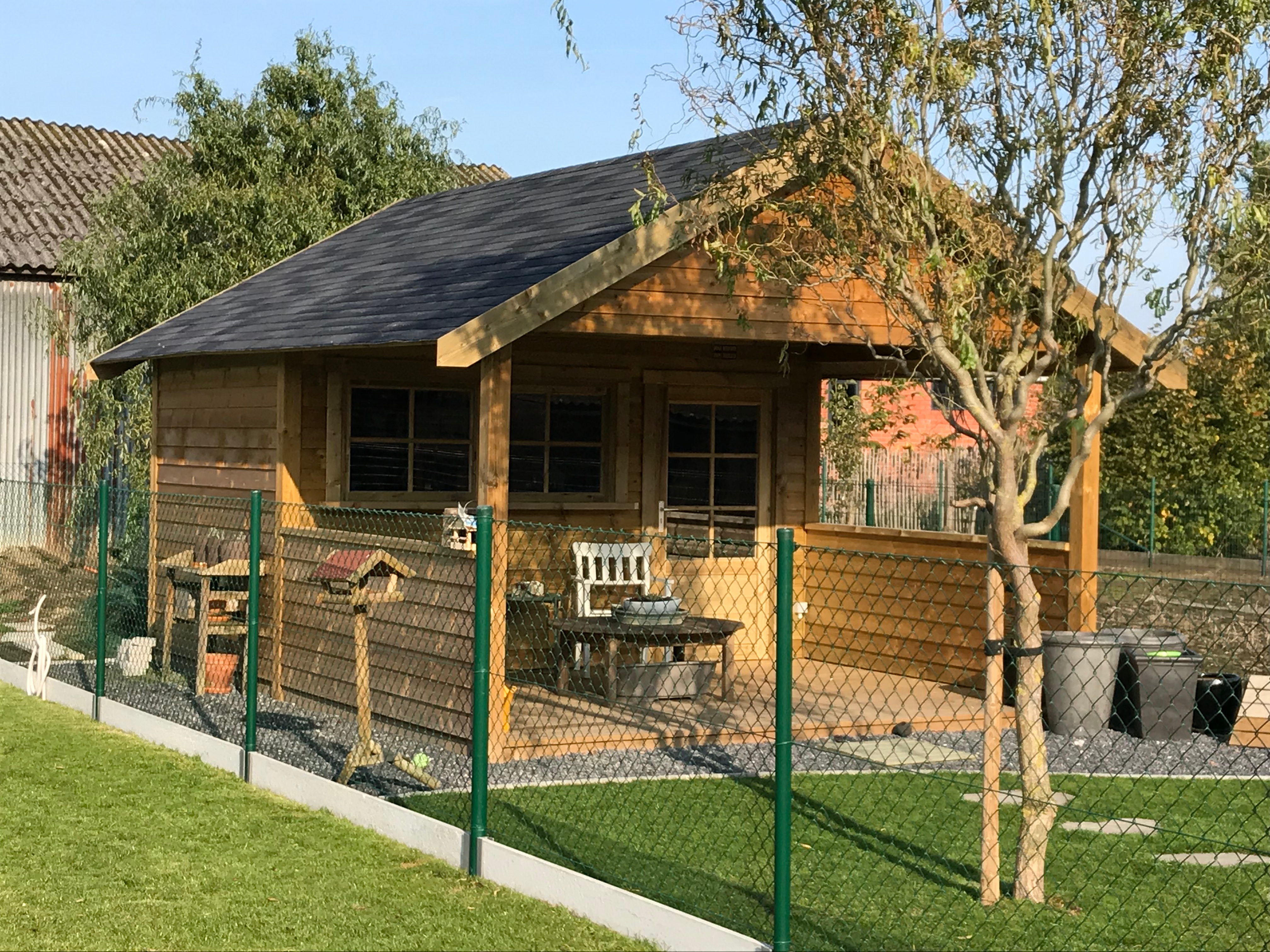 Houten bijgebouw met overdekt terras in een tuin