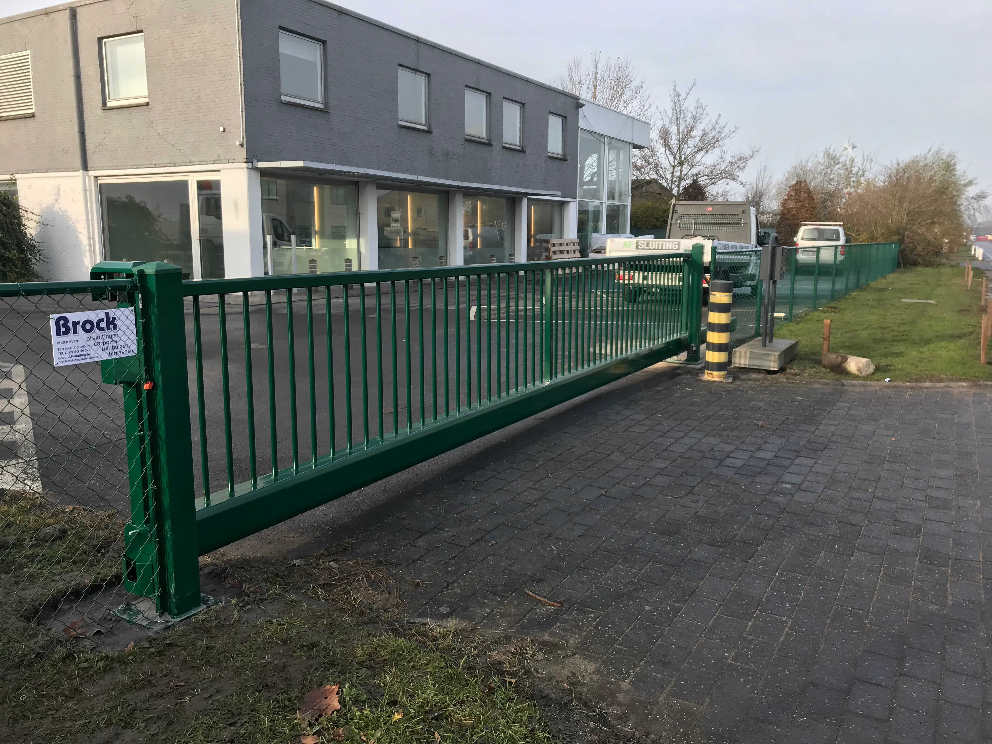 Groene manuele industriële schuifpoort in metaal geplaatst bij een bedrijfssite in Brugge.