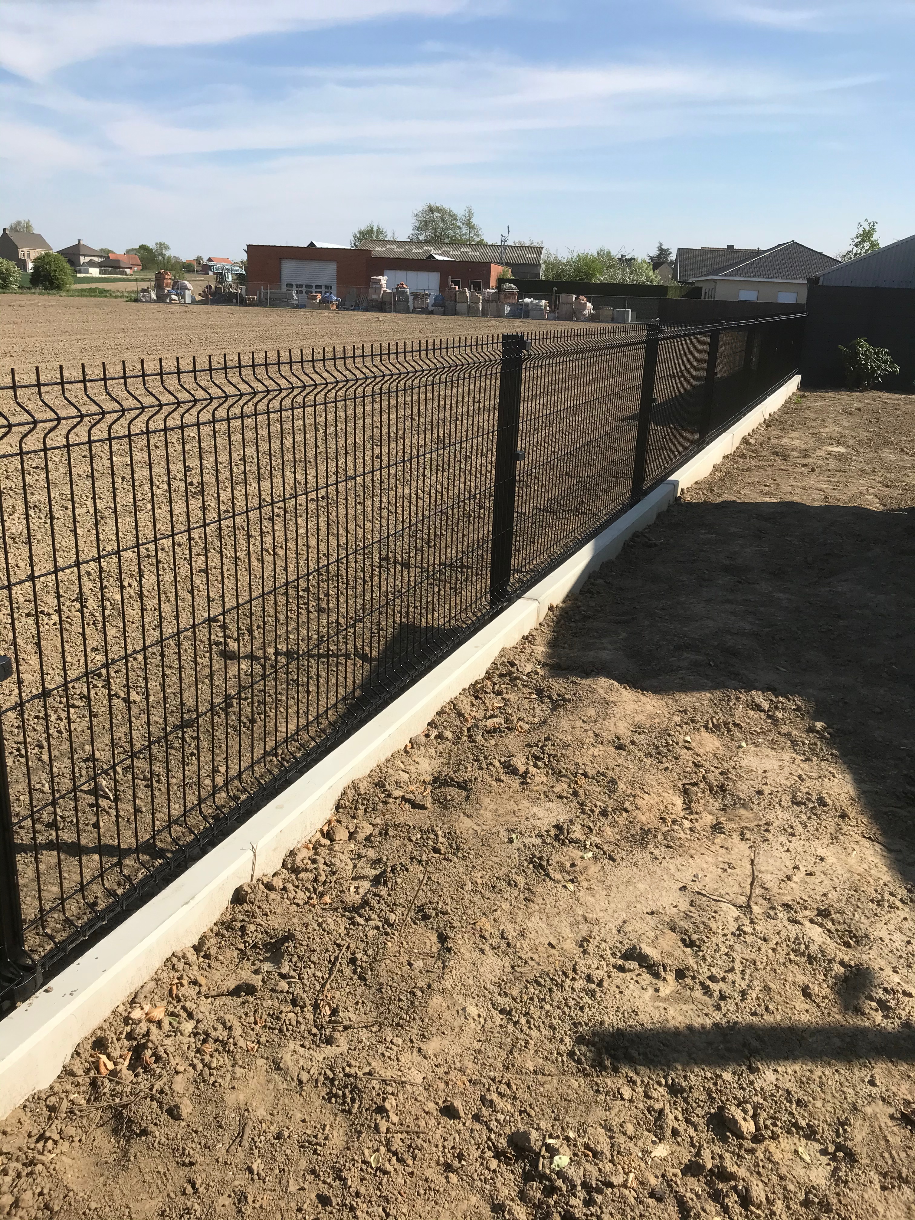 Zwarte 3D draadpanelen geplaatst op een betonnen keerwand langs een perceel in Staden.