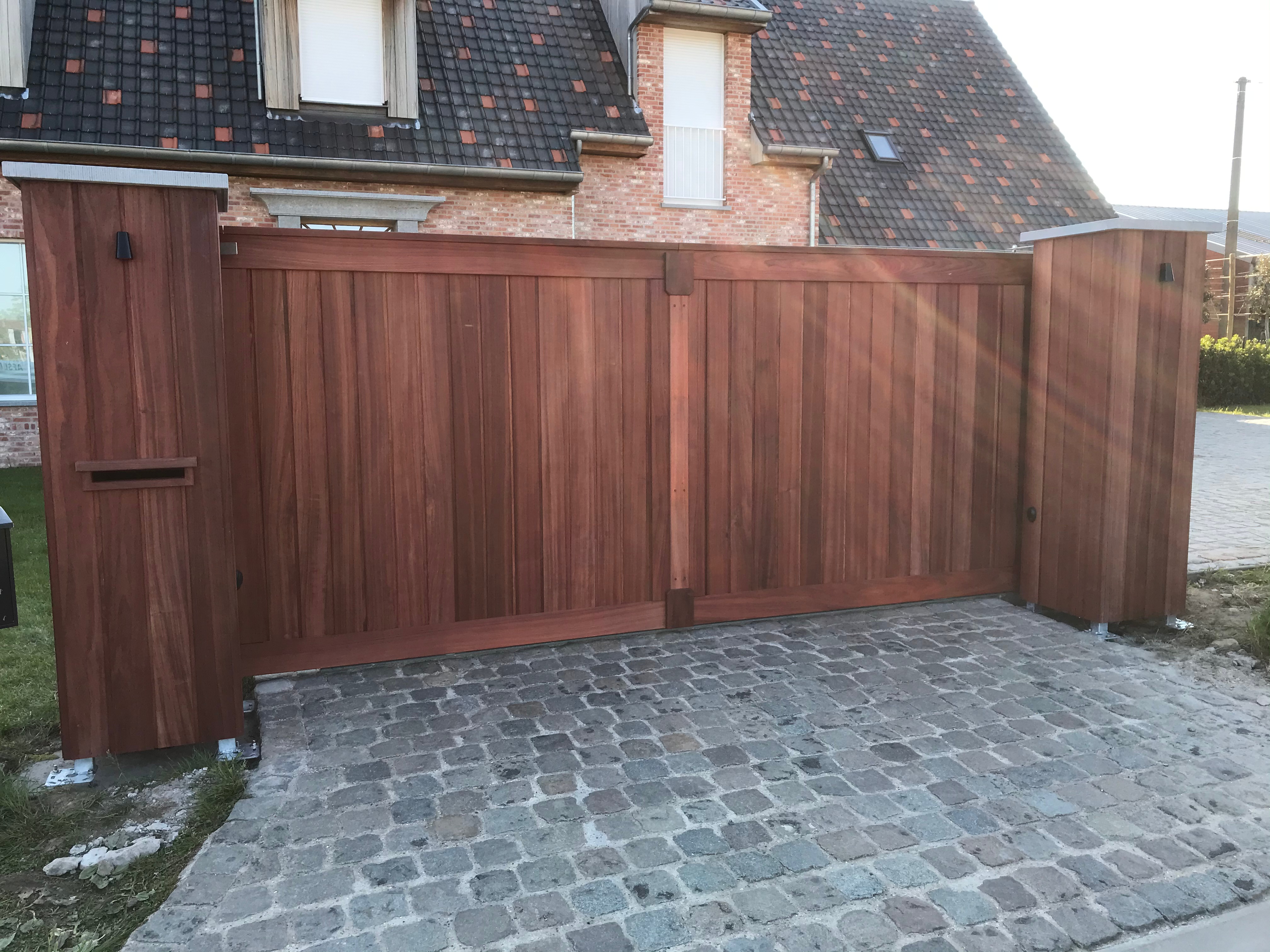 Geautomatiseerde padouk schuifpoort met zuilen en geïntegreerde brievenbus in Torhout