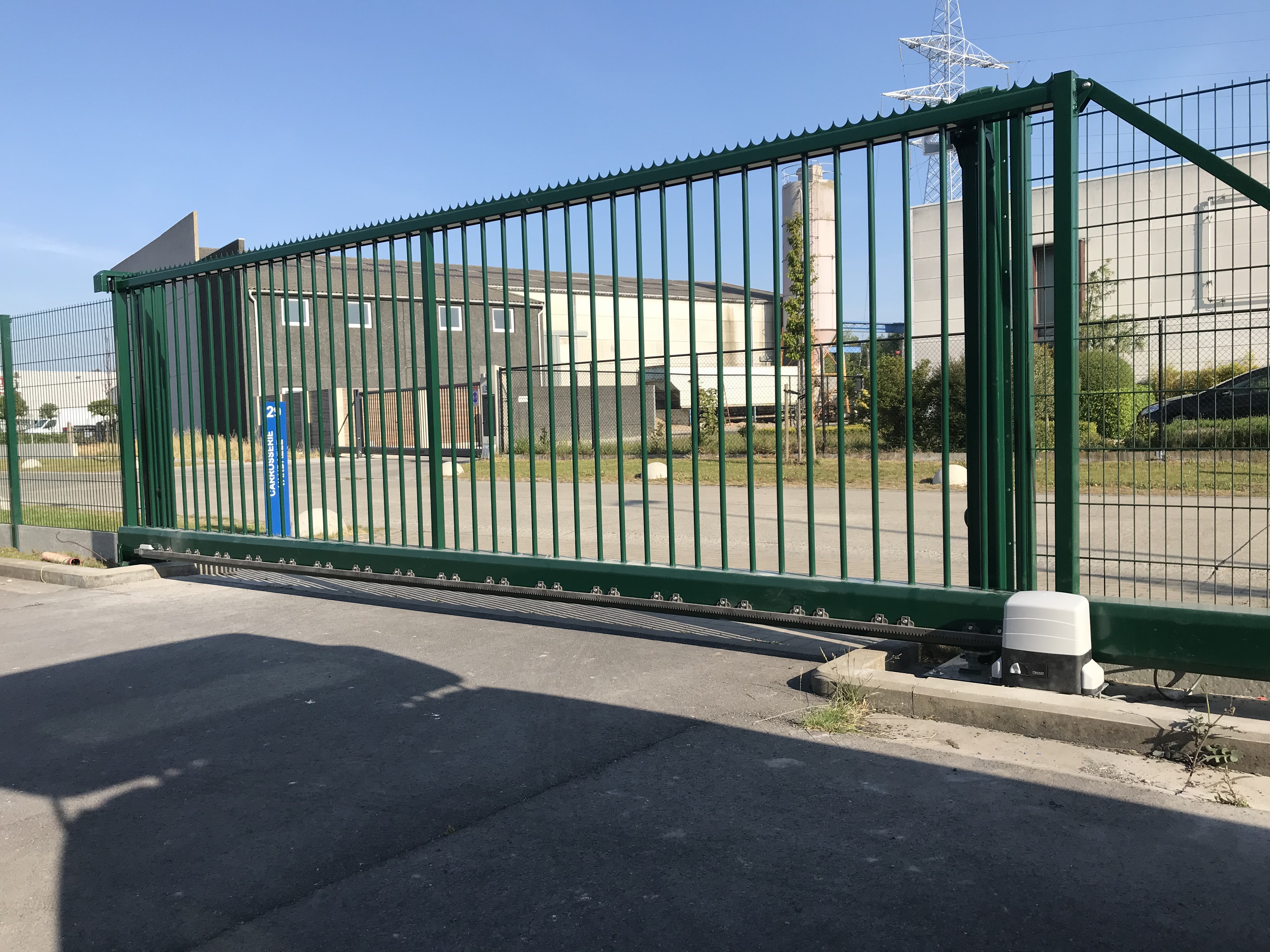 Groene geautomatiseerde industriële schuifpoort geplaatst aan een bedrijfsterrein in Bredene.