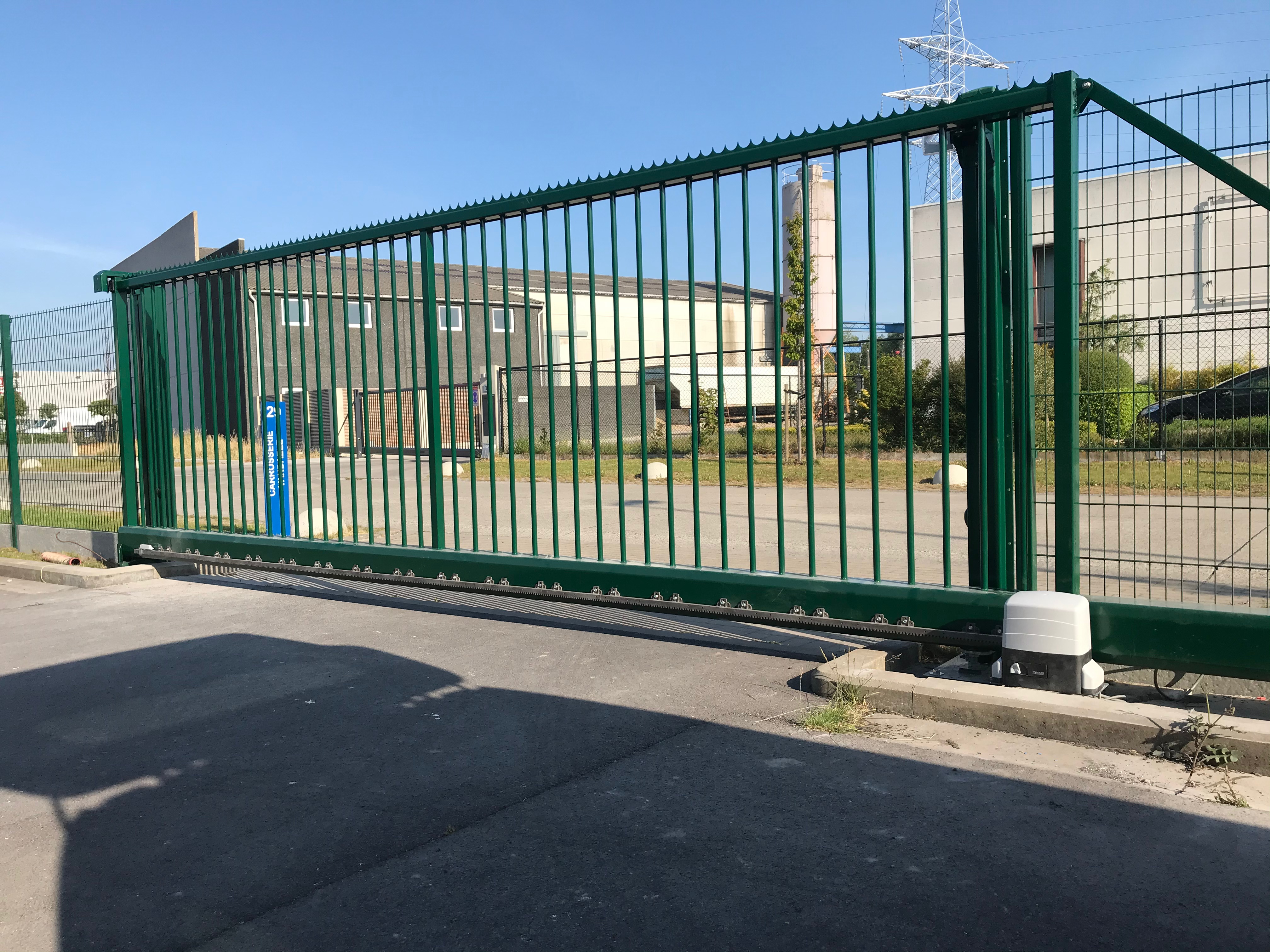 Groene geautomatiseerde metalen schuifpoort geplaatst bij een bedrijfssite in Bredene.