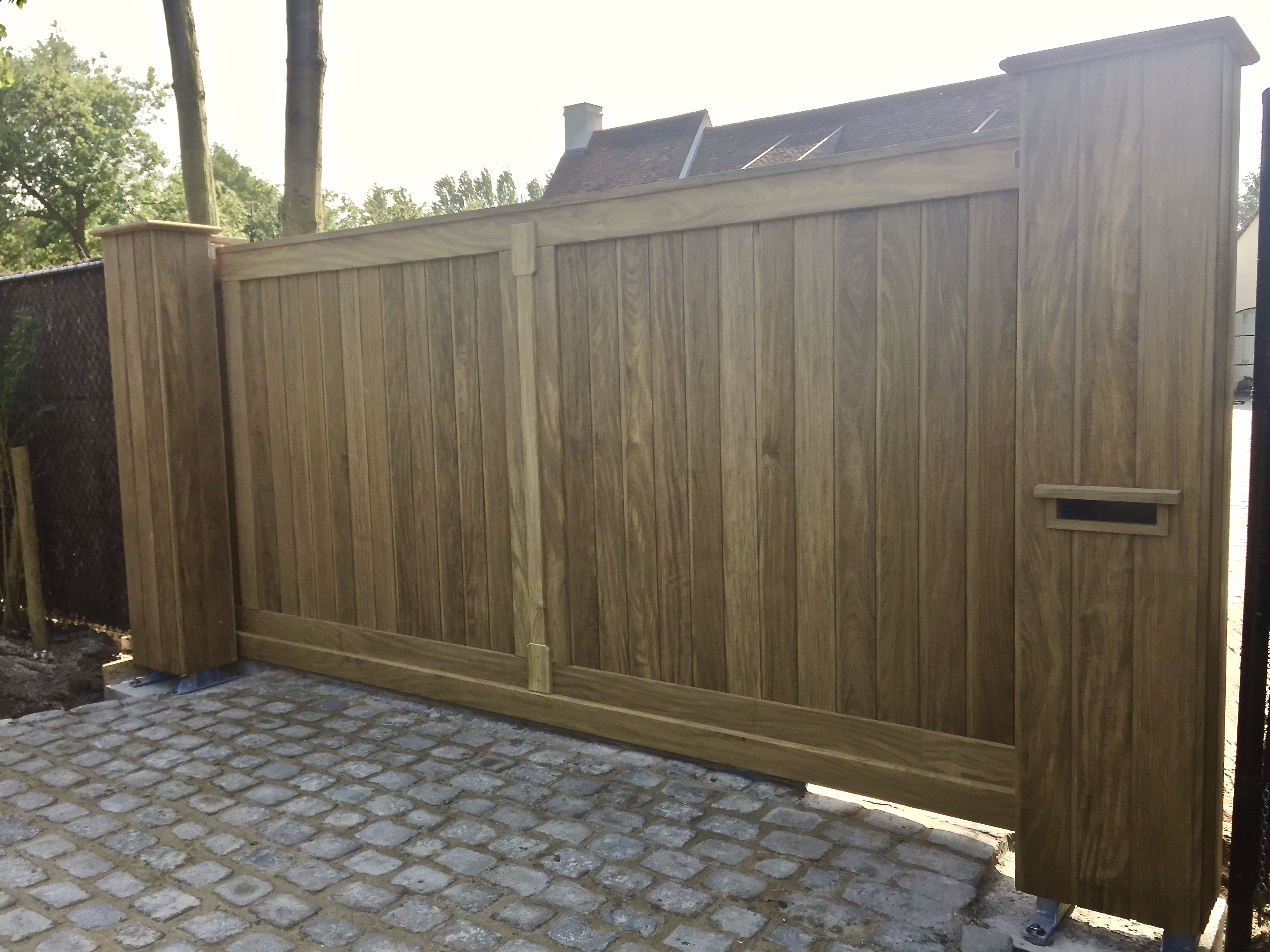 Houten schuifpoort in afrormosia bij een woning in Damme