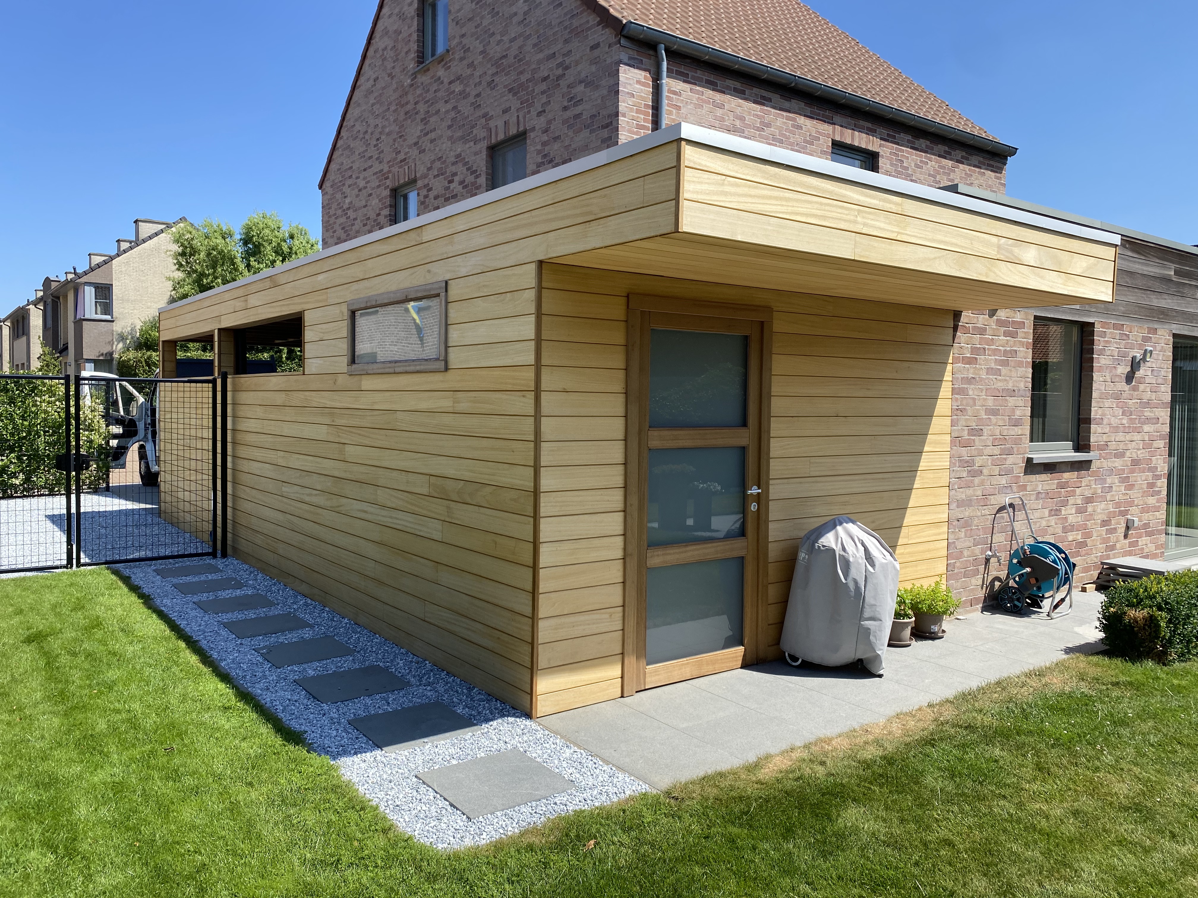 Modern houten bijgebouw met plat dak in een tuin in Staden