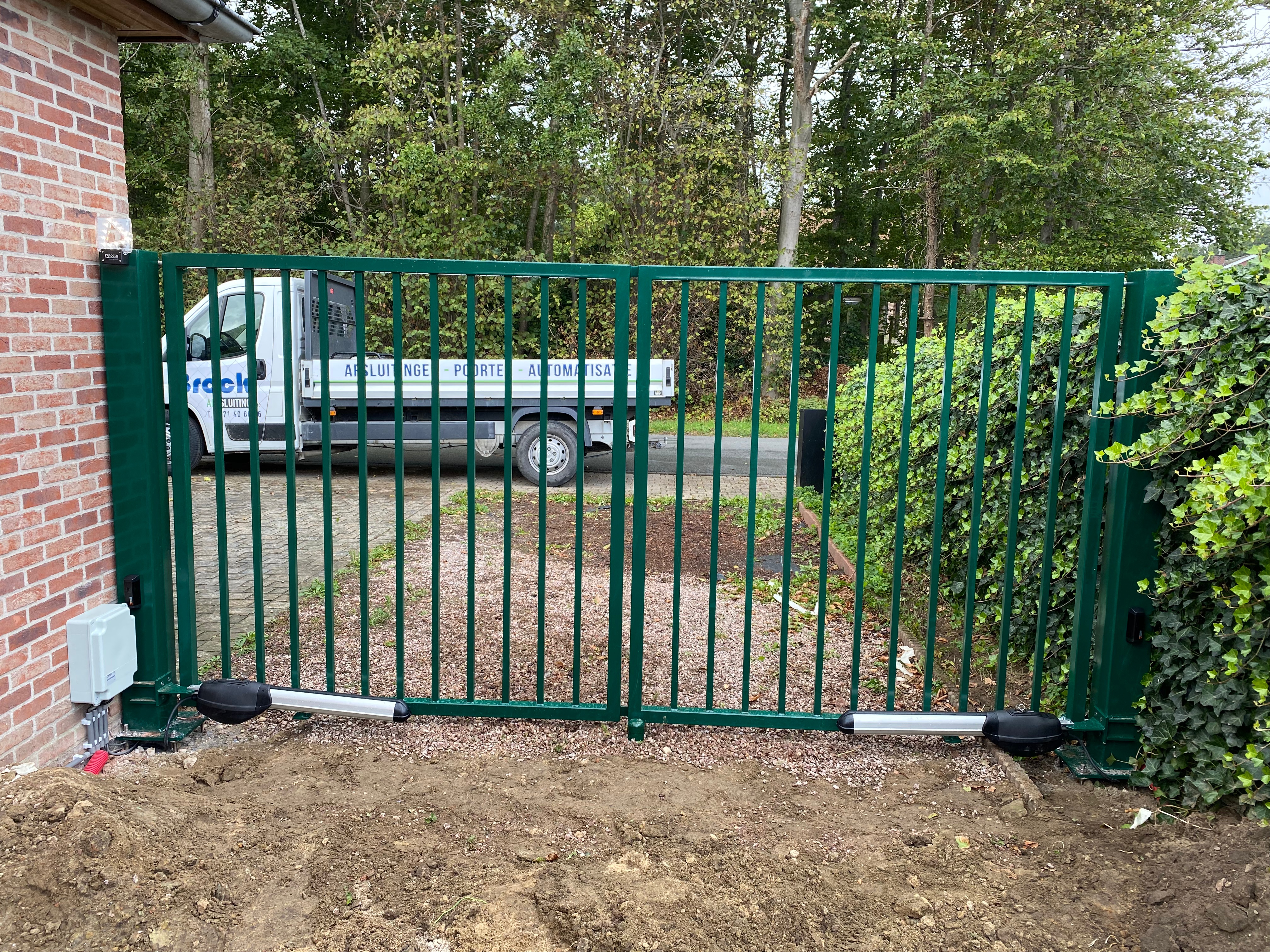 Groene metalen dubbel opendraaiende spijlenpoort met automatisatie geplaatst in Wijnendale.