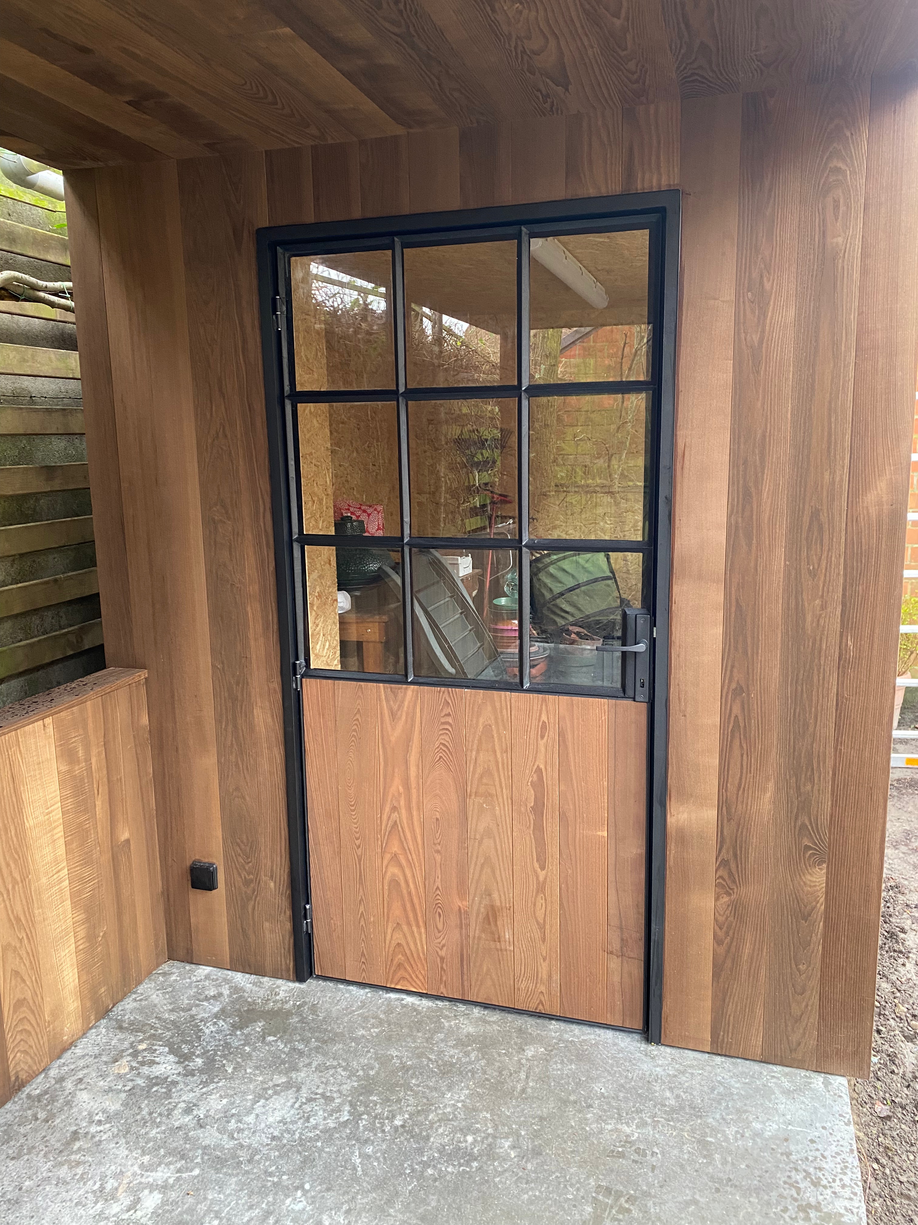 Houten bijgebouw met stalen deur en houtbekleding in Gistel