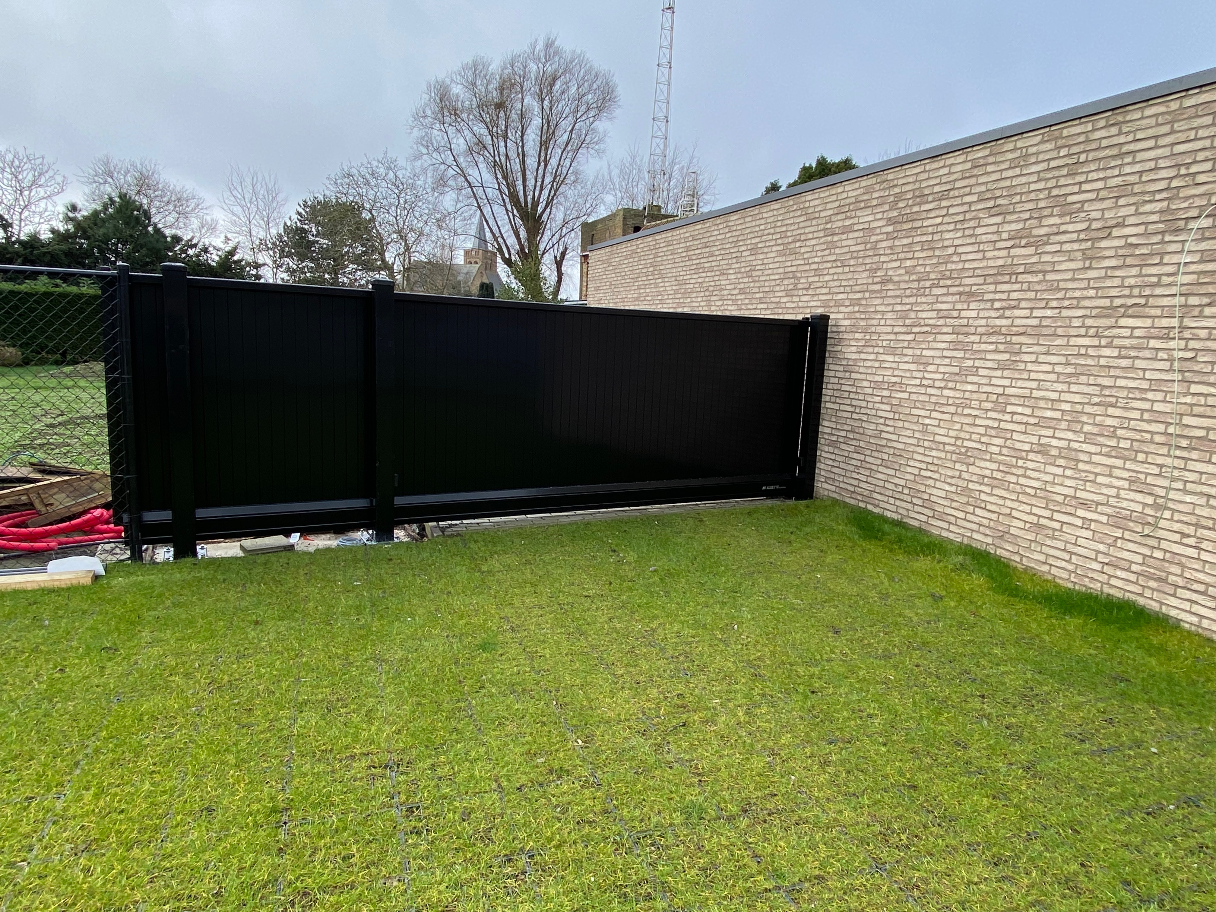 Aluminium schuifpoort met geïntegreerde automatisatie geplaatst in Westende.