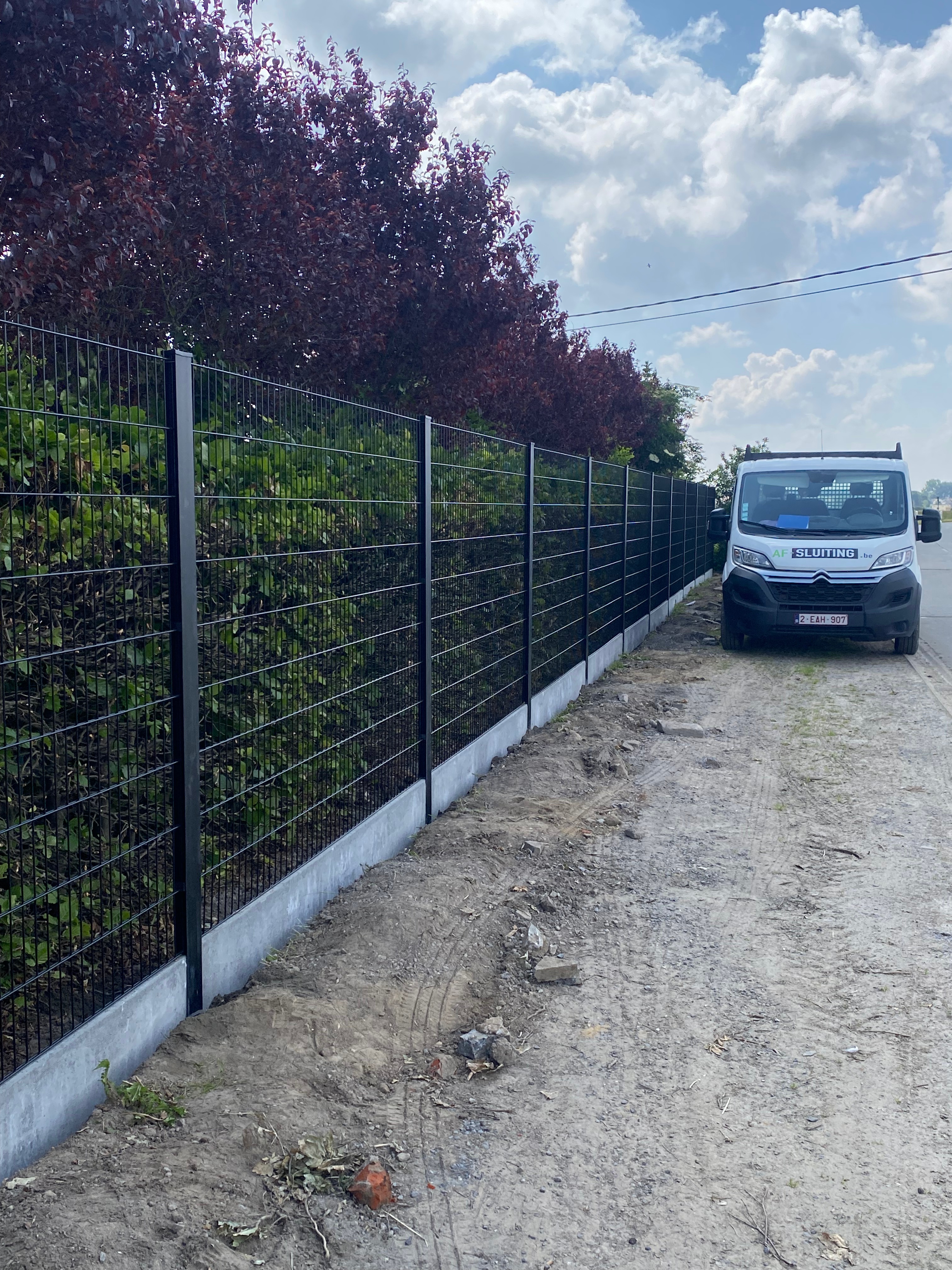 Zwarte dubbelstaafmat afsluiting met H-gleufpalen en betonplaten, geplaatst in Sleihage.