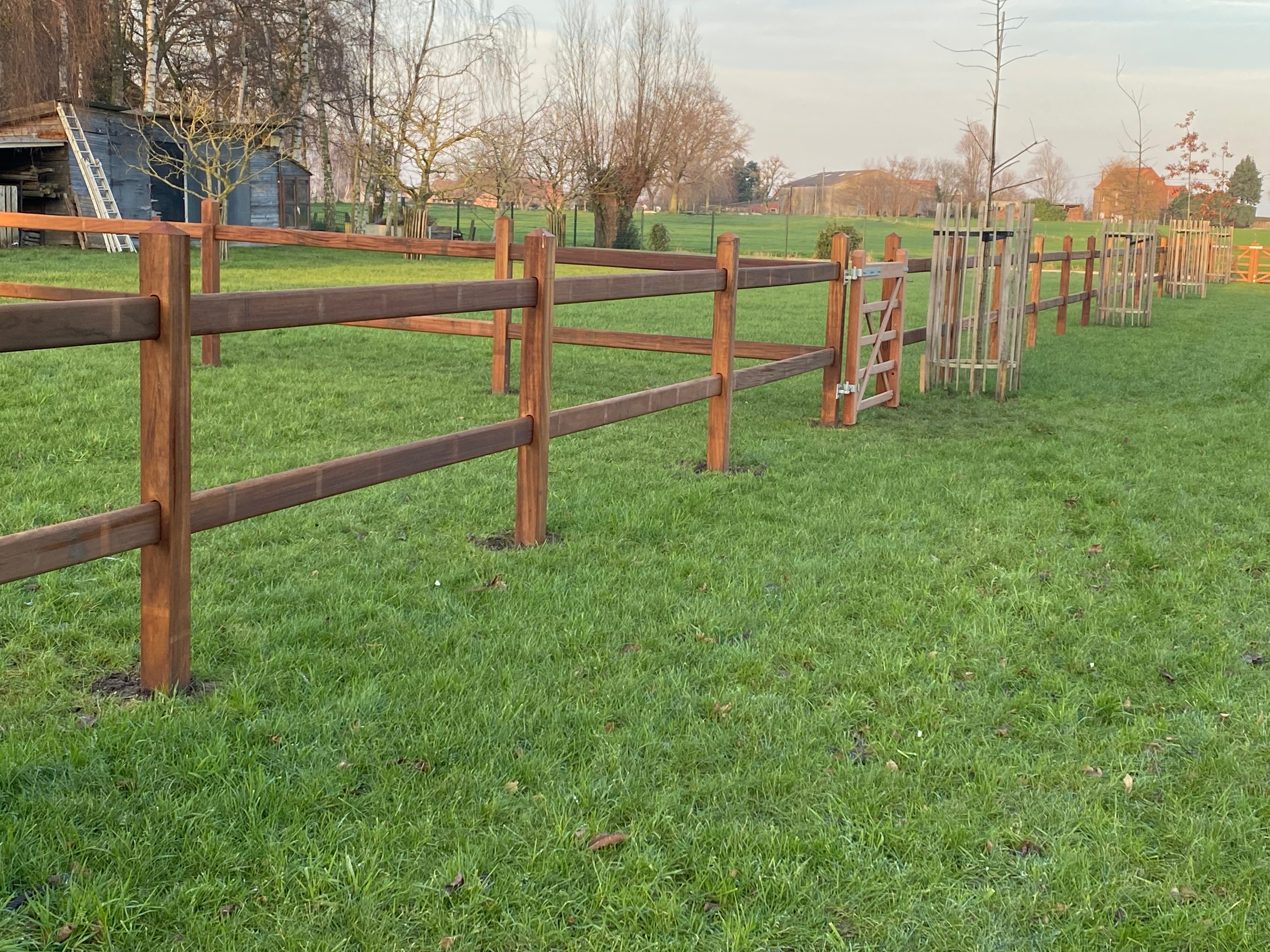Houten weideafsluiting met landelijke poort in Engelse stijl, geplaatst in Zarren.
