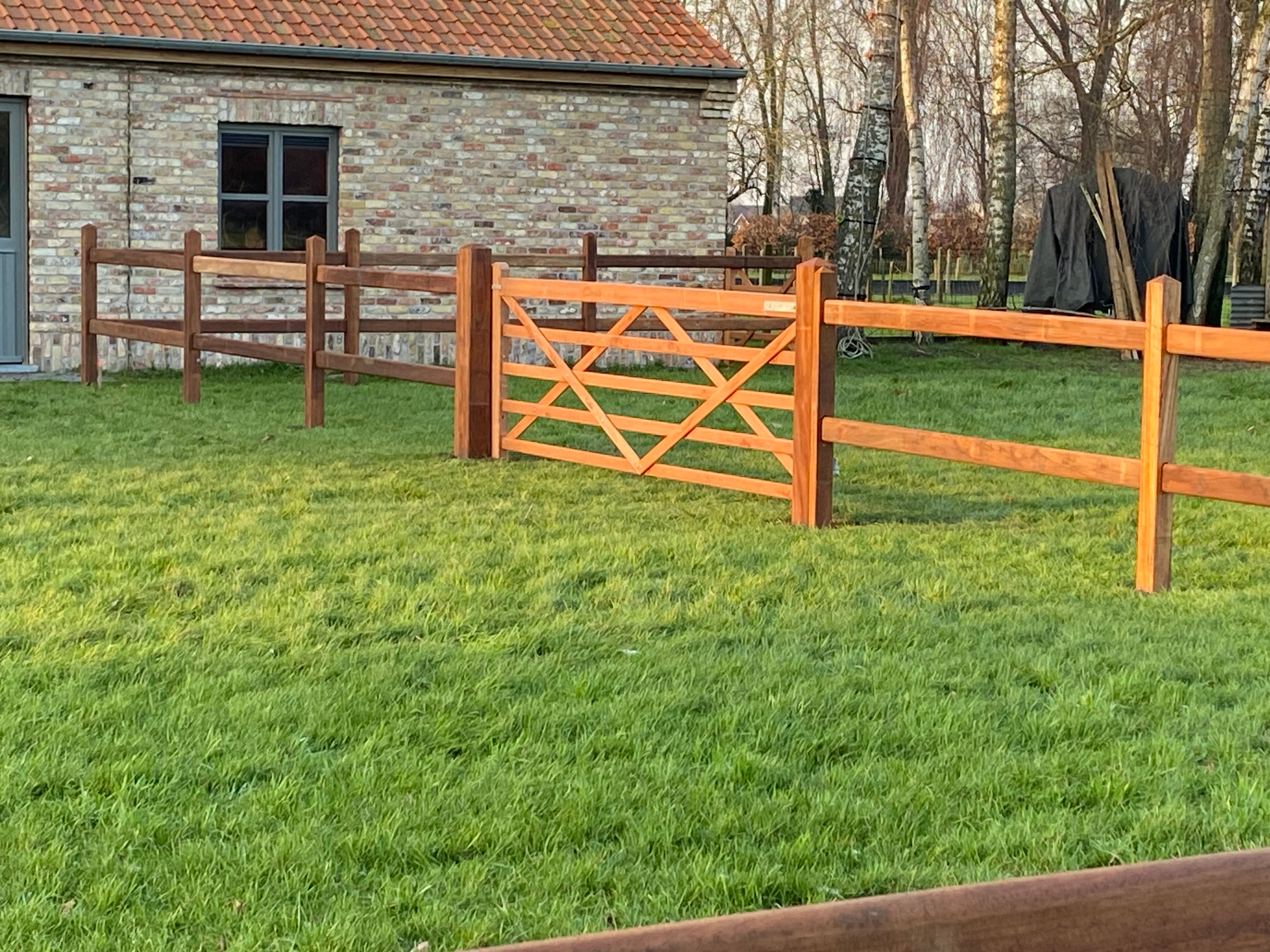 Houten weideafsluiting met landelijke poort in Engelse stijl, geplaatst in Zarren.
