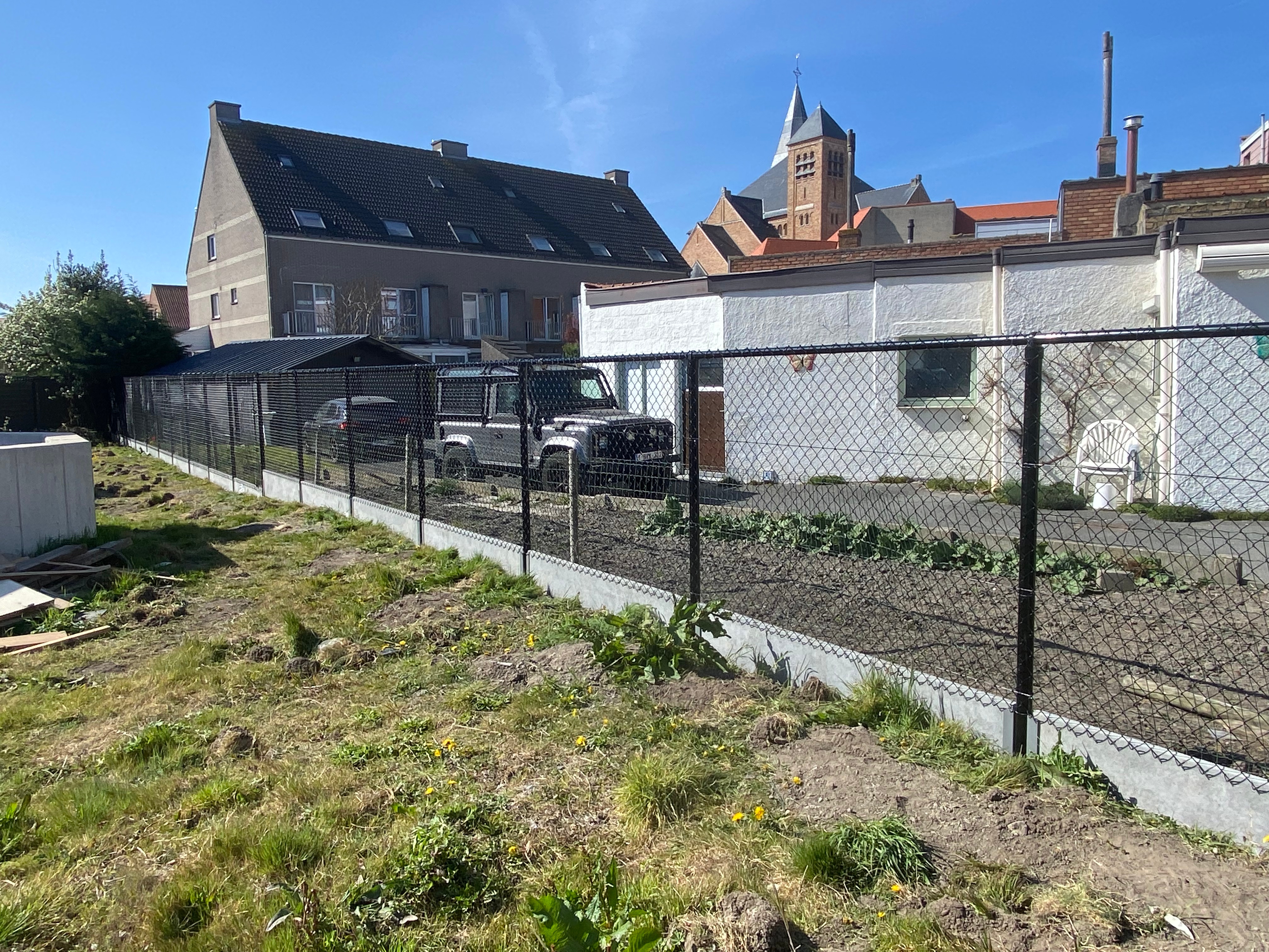 Draadafsluiting met betonplaat onderaan en bovenbuis voor extra stevigheid, geplaatst in Middelkerke.